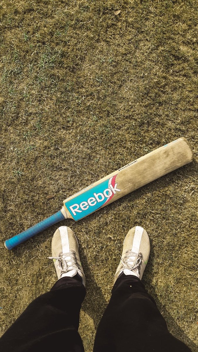 a baseball bat laying on the ground next to a person's feet